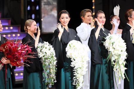 　黒紋付きに緑の袴姿でファンに手を振る宙組トップスター真風涼帆（中央）、トップ娘役・潤花（左）、寿つかさ組長（右）＝宝塚大劇場