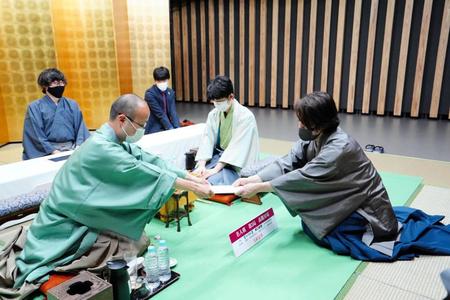 　封じ手を手渡す渡辺明名人（左）。見守る藤井聡太竜王（中央）＝日本将棋連盟提供