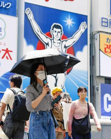 　強い日差しの中、日傘を差して歩く女性ら＝大阪・ミナミ