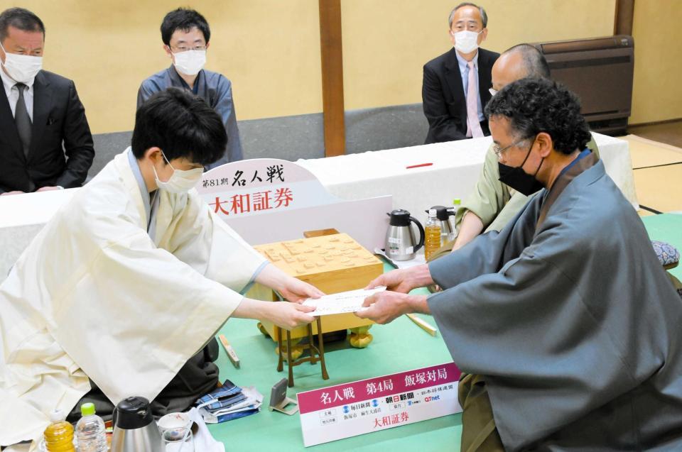 　封じ手を渡す藤井聡太竜王（日本将棋連盟提供）