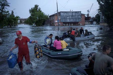 　水浸しになったウクライナ南部ヘルソン市内で避難する人たち＝６日（ＡＰ＝共同）