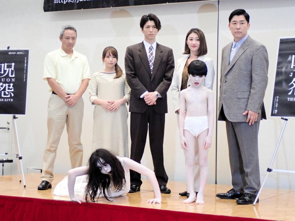 「呪怨　ＴＨＥ　ＬＩＶＥ」の制作発表会見に出席した（左から）いしだ壱成、大場美奈、小林準弥、原幹恵、あべこうじとサプライズ登場した伽椰子（左下）、俊雄（右手前）