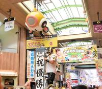 　尼崎中央３丁目商店街で大勢のファンとマジック０点灯を祝うプロレスラーの空牙