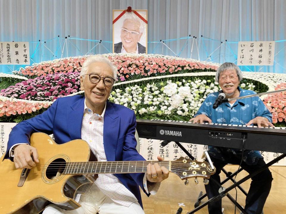 　祭壇の前で弾き語りを披露した荒木とよひさ氏（左）と岡千秋氏