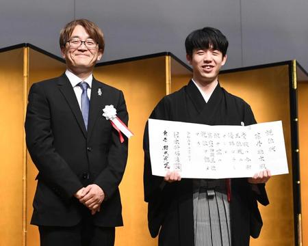 　羽生善治会長（左）から渡された就位状を笑顔で手にする藤井聡太王位（撮影・園田高夫）