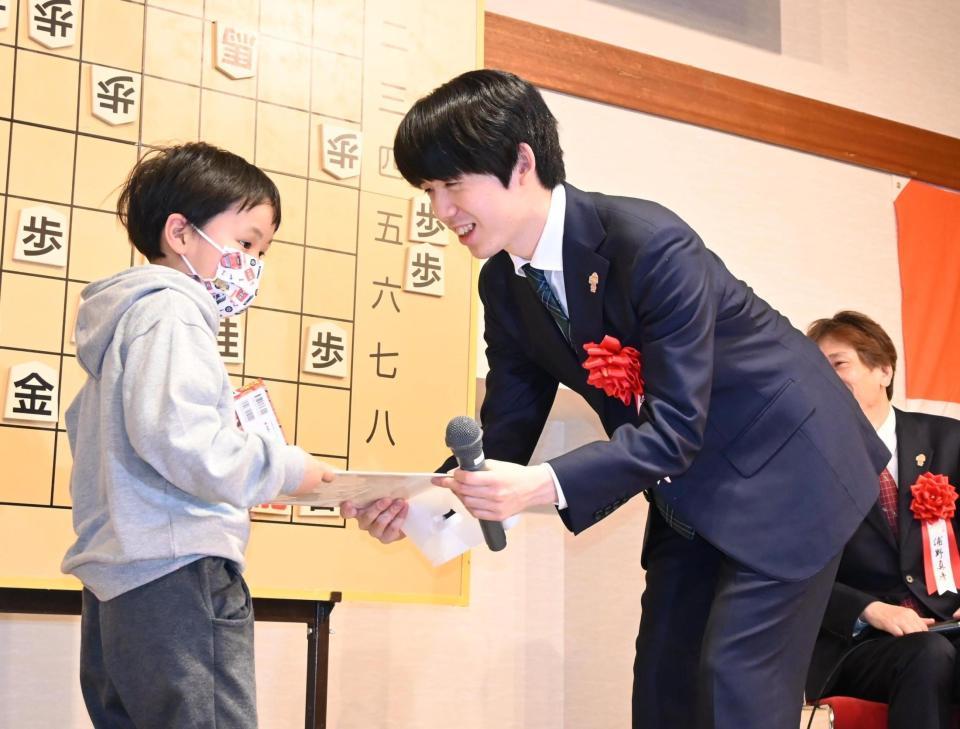 　抽選会で当選した子どもに、直筆の揮毫（きごう）をプレゼントする藤井聡太王将（撮影・高部洋祐）