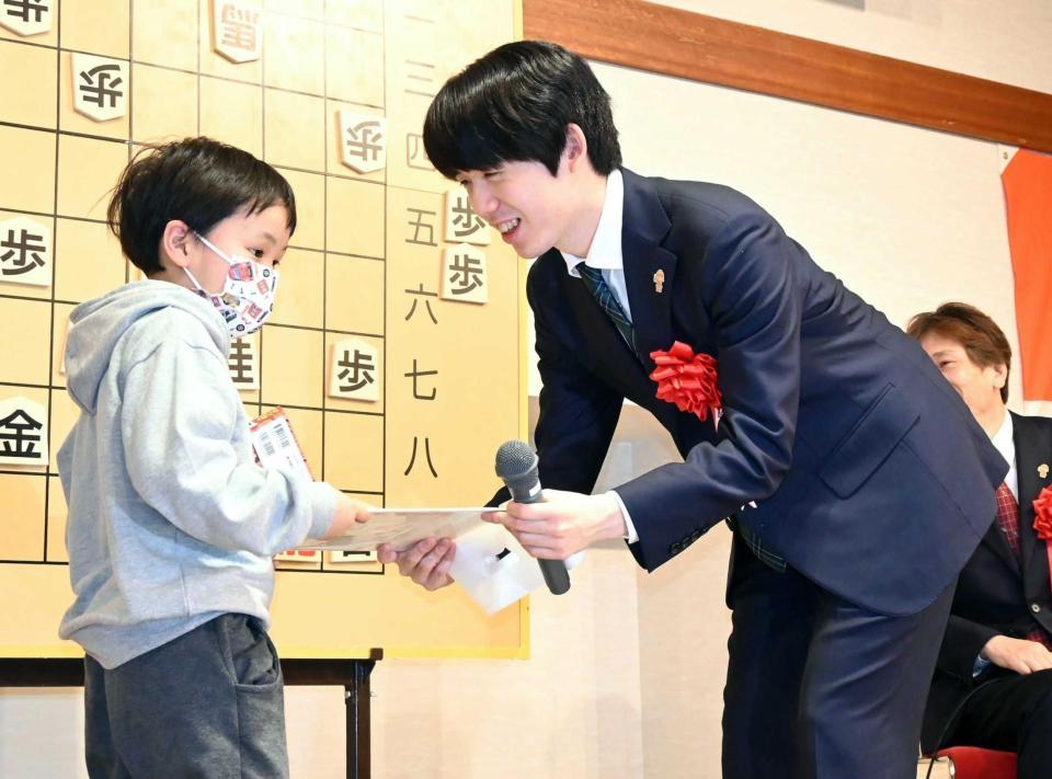 　抽選会で当選した子どもにプレゼントを渡す藤井聡太王将（撮影・高部洋祐）