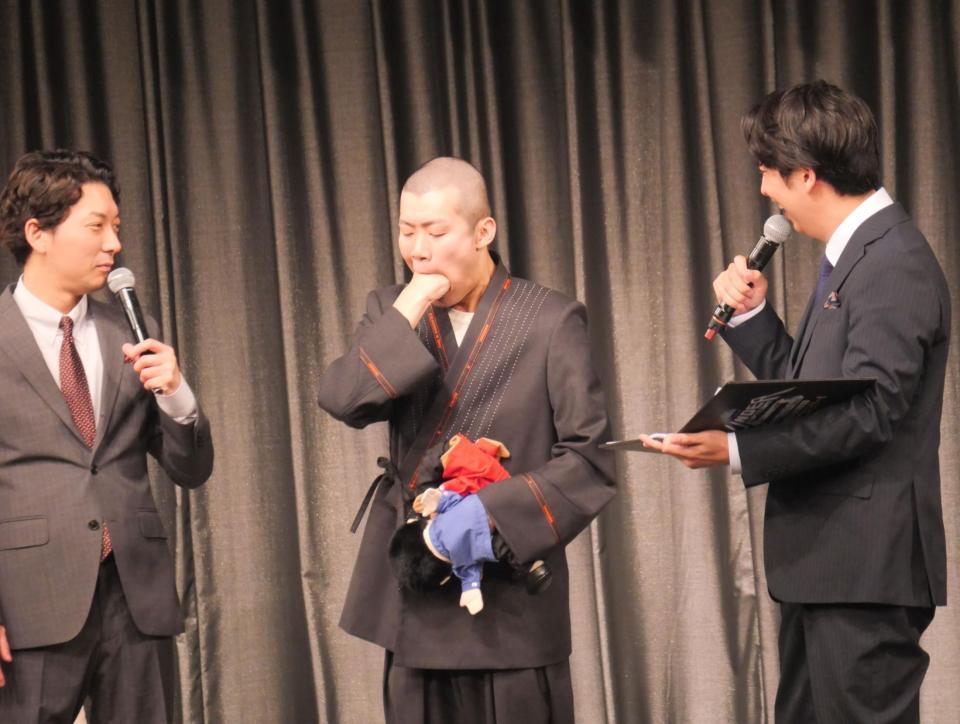 　口に手が丸々入ることを証明した清川雄司（中央）と見つめる嶋佐和也（左）と屋敷裕政