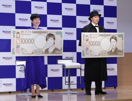 　自分の写真が１万円札になったボードを持ち、笑顔を見せる有働由美子（左）と尾上松也（撮影・西岡正）