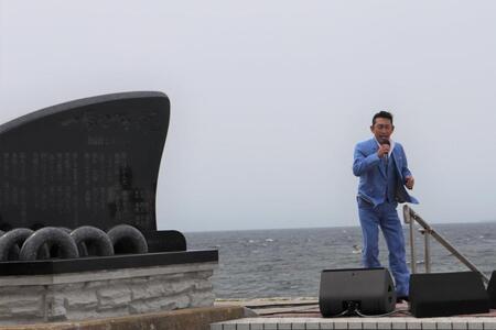 　歌碑の前で津軽海峡をバックに歌う福田こうへい