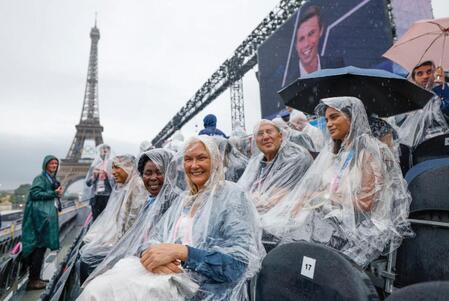 　雨の中、開会式が行われるトロカデロ庭園で開幕を待つ観客。奥はエッフェル塔（共同）