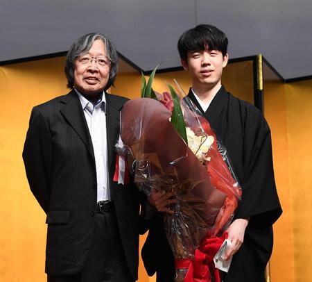 　大崎善生さん（左）から花束を渡され、祝福される藤井聡太王位＝２０２３年１１月撮影