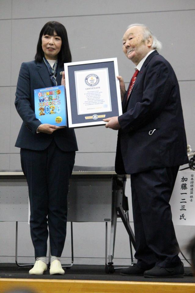 　立ち上がりギネス世界記録認定証を受け取る加藤一二三九段