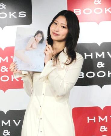 　写真集を掲げて笑顔の山下エミリー