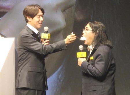 　コカドケンタロウ（左）にケーキを食べさせられる中岡創一