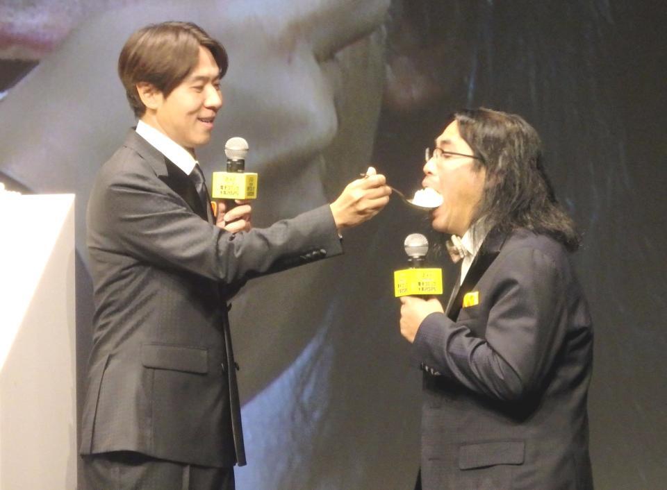 　コカドケンタロウ（左）にケーキを食べさせられる中岡創一