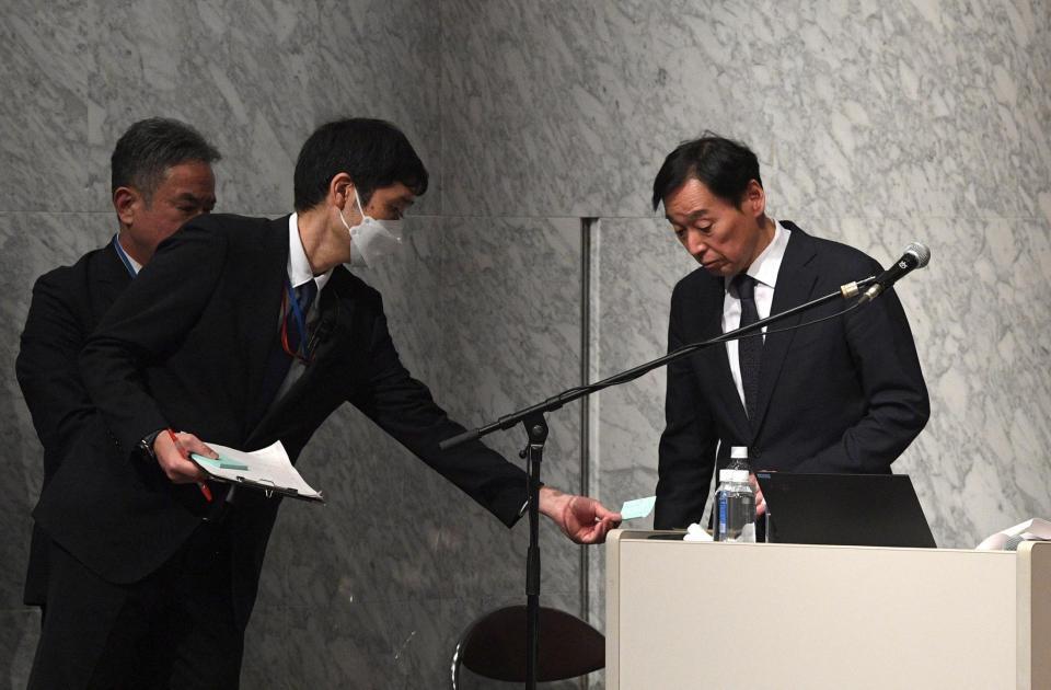 　会見の進行をする上野陽一広報局長とメモを渡すスタッフ（撮影・佐々木彰尚）