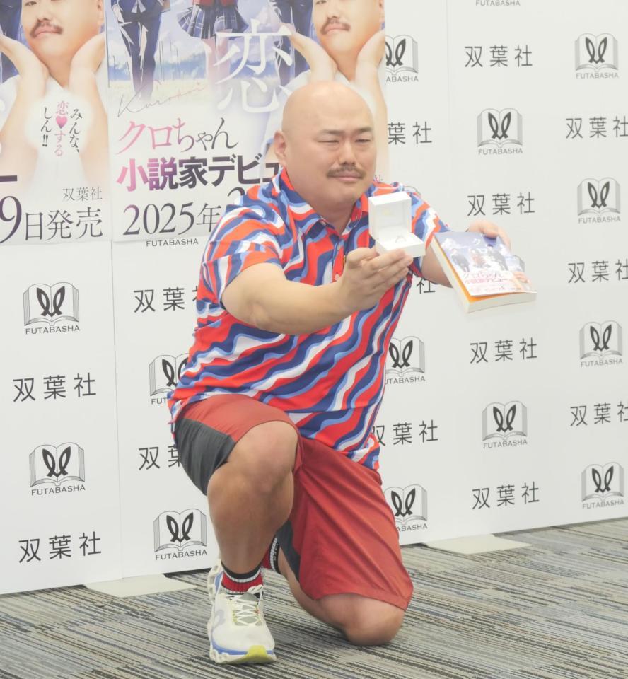 　報道陣から求められ、プロポーズをするように指輪と著書を悲しげな表情でアピールするクロちゃん