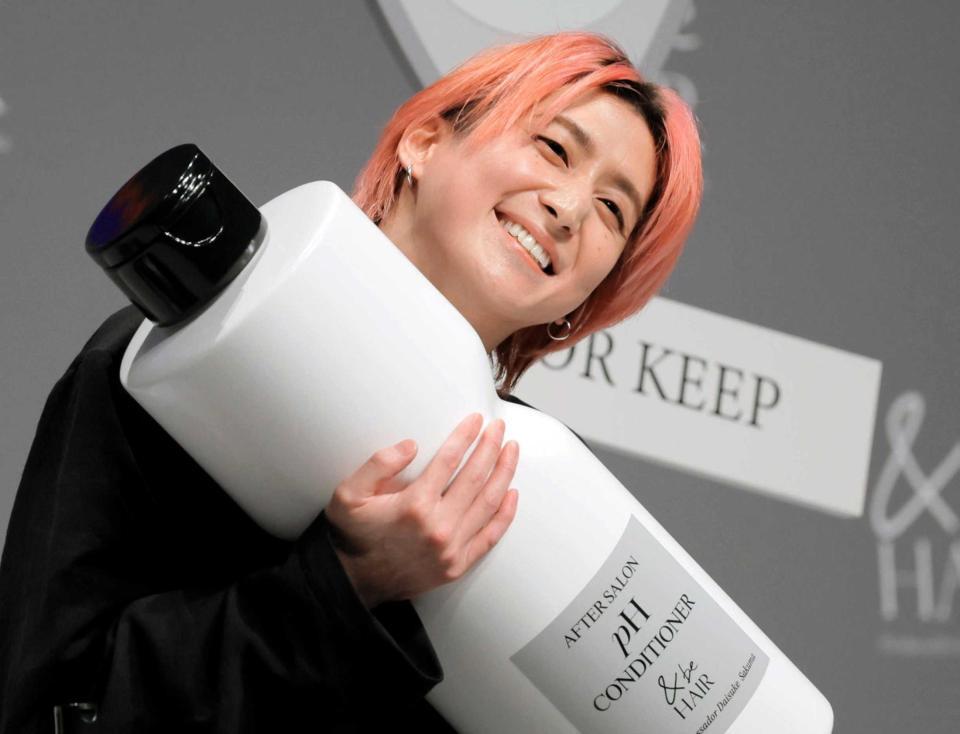 　商品を手に笑顔の佐久間大介