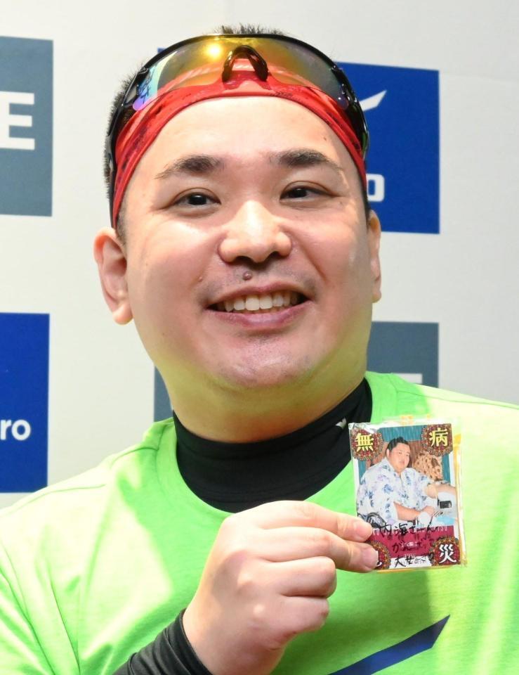 　沿道の子どもからプレゼントされたという大相撲カードを手に笑顔を見せるミルクボーイ・内海崇（撮影・高部洋祐）