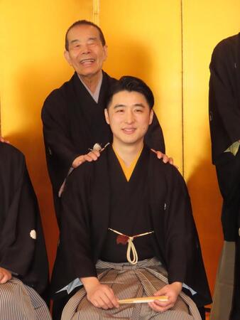 　真打昇進襲名披露会見で林家木久彦（前）の肩に手を置く林家木久扇