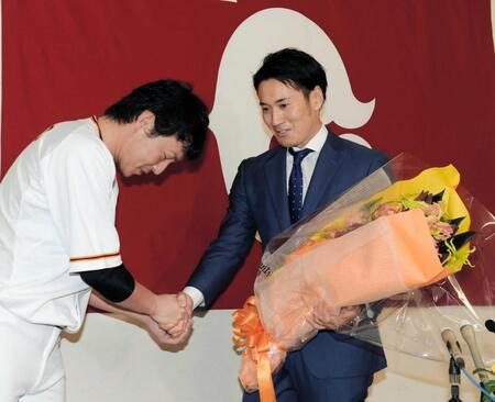 　引退会見で長野久義から花束を受け取る片岡治大氏（１７年１０月）
