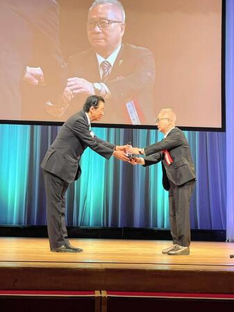 　大平理事長から記念品を受け取る谷会長（右）