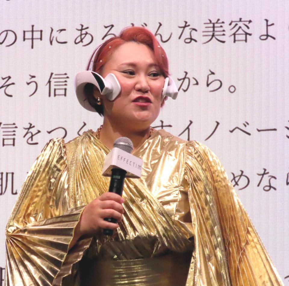 　クイックフェイシャルトレーナーを着用しマイクを握るバービー