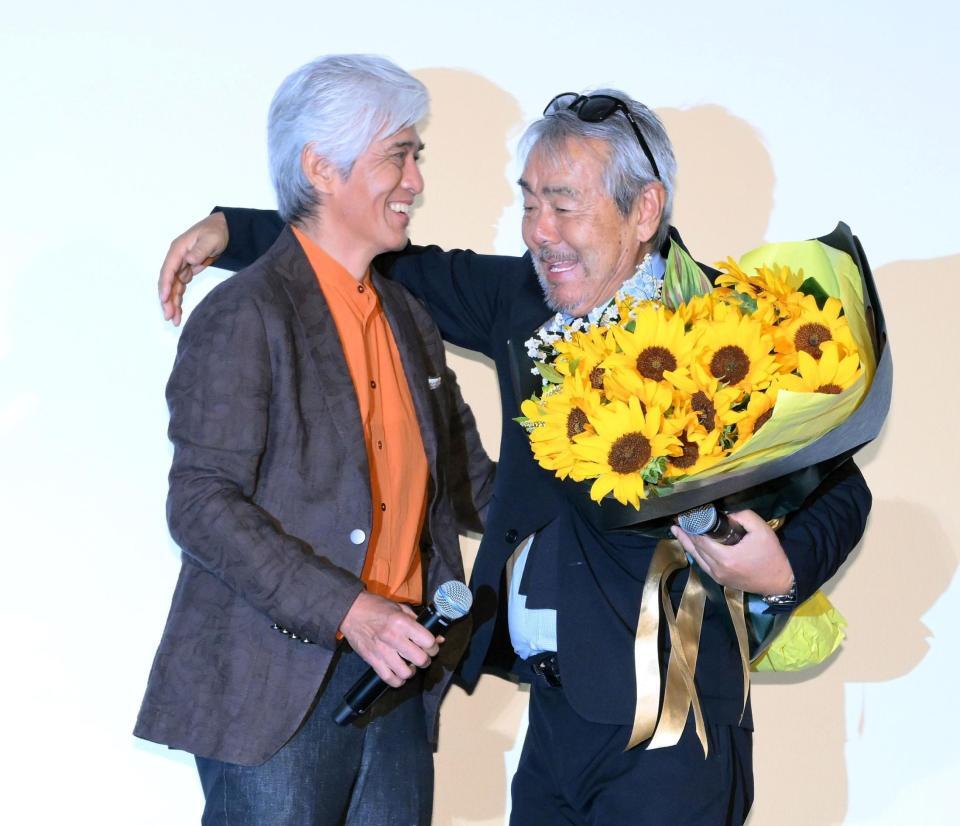 　サプライズ登場した佐藤浩市（左）から誕生日を祝う花束を受け取り、ハグを交わす寺尾聰（撮影・伊藤笙子）
