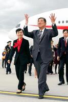 　カナダ・カルガリー国際空港に到着し、雨天に手を広げる石破首相。左は妻の佳子さん（共同）