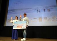 　海岸の映像を背に手を振る小泉今日子（左）と中井貴一（撮影・西岡正）