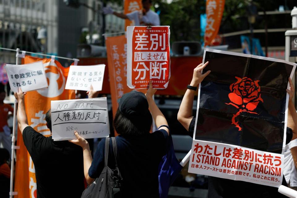 　参政党候補者の街頭演説に対し、抗議のメッセージを掲げる人たち＝東京・渋谷