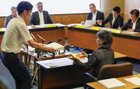 　静岡県伊東市議会の百条委員会で証人尋問に応じ、確認のために東洋大の卒業アルバムを受け取る田久保真紀市長（右）