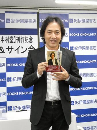　自身の書籍を持って写真に応じる秋川雅史
