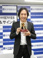 　自身の書籍を持って写真に応じる秋川雅史