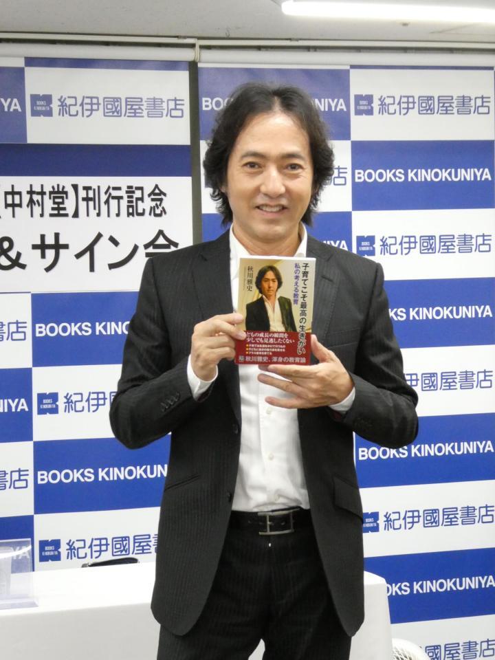 　自身の書籍を持って写真に応じる秋川雅史