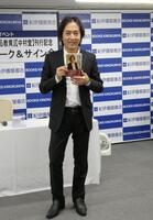 　自身の書籍を持って写真に応じる秋川雅史