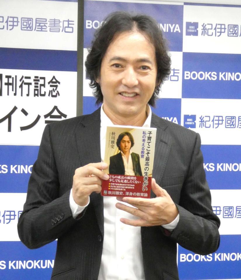 　自身の書籍を持って写真に応じる秋川雅史