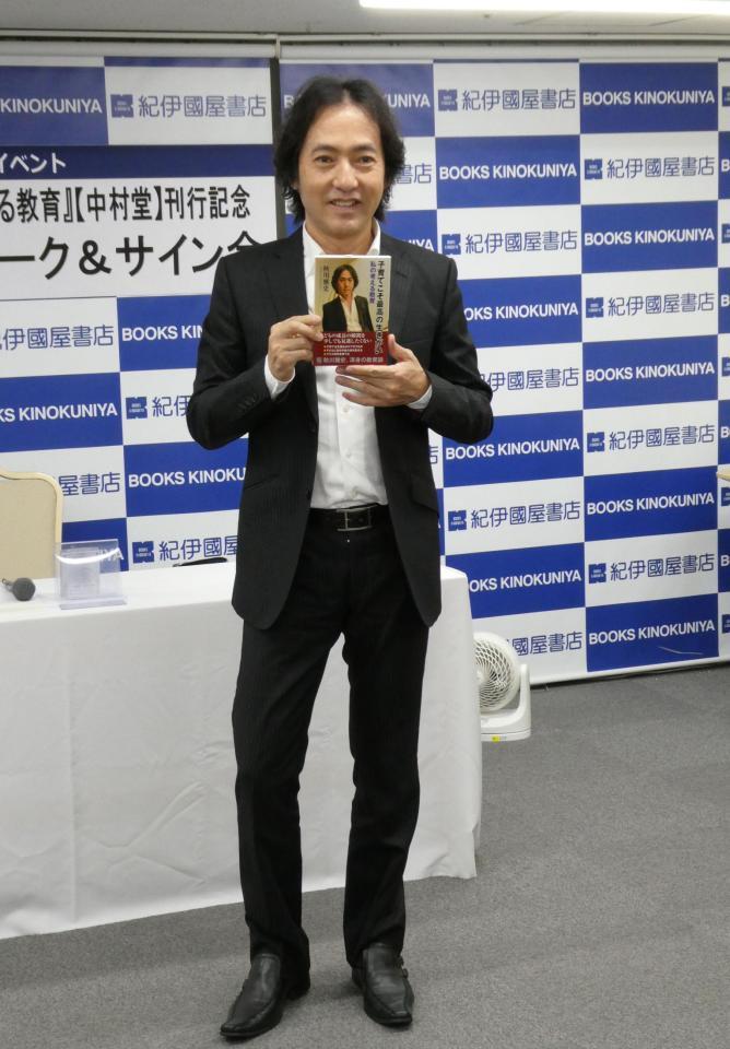 　自身の書籍を持って写真に応じる秋川雅史