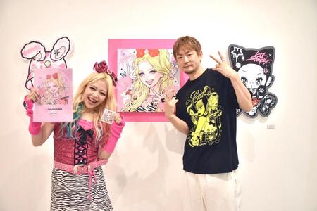 　ｉｓａｙａｍａｘ氏（右）作の自身をモデルにした作品を前に笑顔のエルフ・荒川