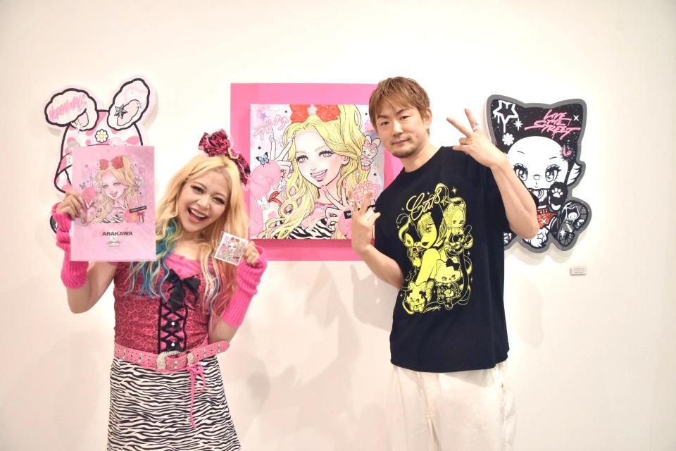 　ｉｓａｙａｍａｘ氏（右）作の自身をモデルにした作品を前に笑顔のエルフ・荒川