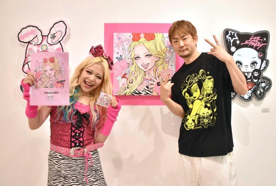 　ｉｓａｙａｍａｘ氏（右）作の自身をモデルにした作品を前に笑顔のエルフ・荒川