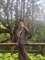 　樹高３２メートルを誇る「大久保のヒノキ」を背景に撮影に応じた青山新＝宮崎・椎葉村