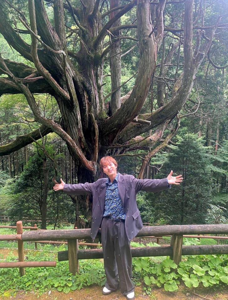 　天然記念物「大久保の大ヒノキ」の前でポーズを決める青山新