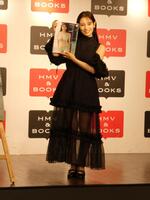 　写真集を持って撮影に応じる葉月くれあ