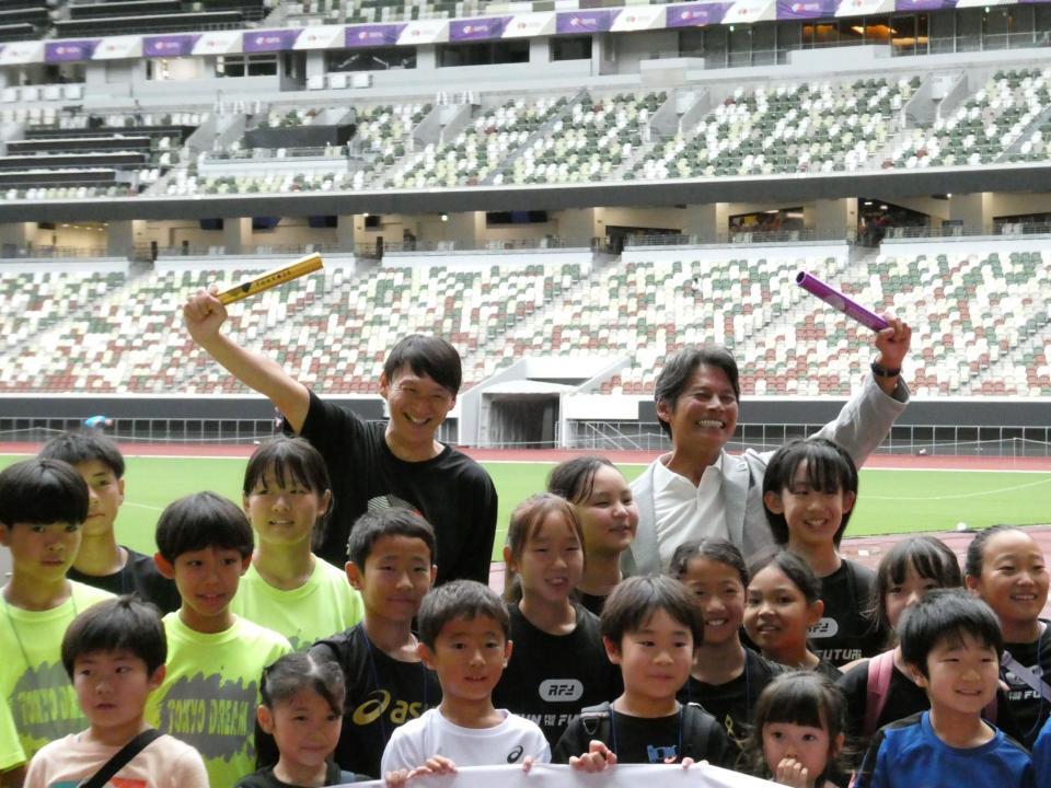 　バトンを掲げる（左奧の）高平慎士さん、（右奥の）織田裕二