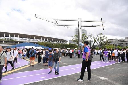 　ブルーインパルスの飛行中止を拡声器で知らせる世界陸上競技選手権大会のスタッフ（右手前）。後方左は国立競技場（撮影・開出牧）