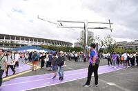 　ブルーインパルスの飛行中止を拡声器で知らせる世界陸上競技選手権大会のスタッフ（右手前）。後方左は国立競技場（撮影・開出牧）