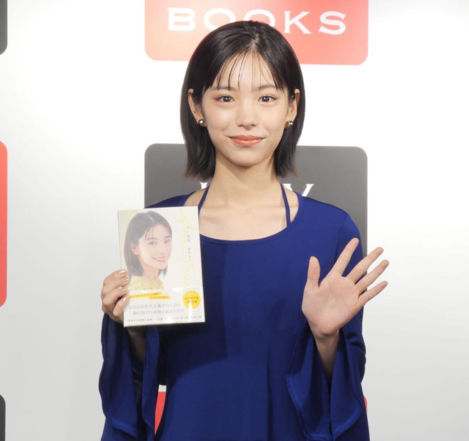 　単行本を手に笑顔を見せる當真あみ