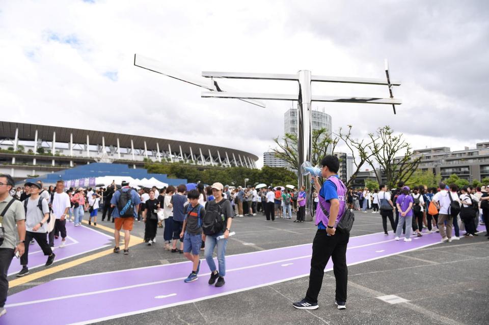 　ブルーインパルスの飛行中止を拡声器で知らせる世界陸上競技選手権大会のスタッフ（右手前）。後方左は国立競技場（撮影・開出牧）
